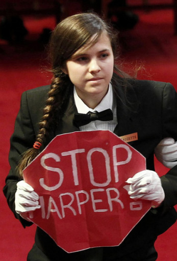 A protester holds a sign reading "Stop Harper" is led from the room as Canada's Governor General David Johnston delivers the Speech from the Throne in the Senate chamber on Parliament Hill in Ottawa